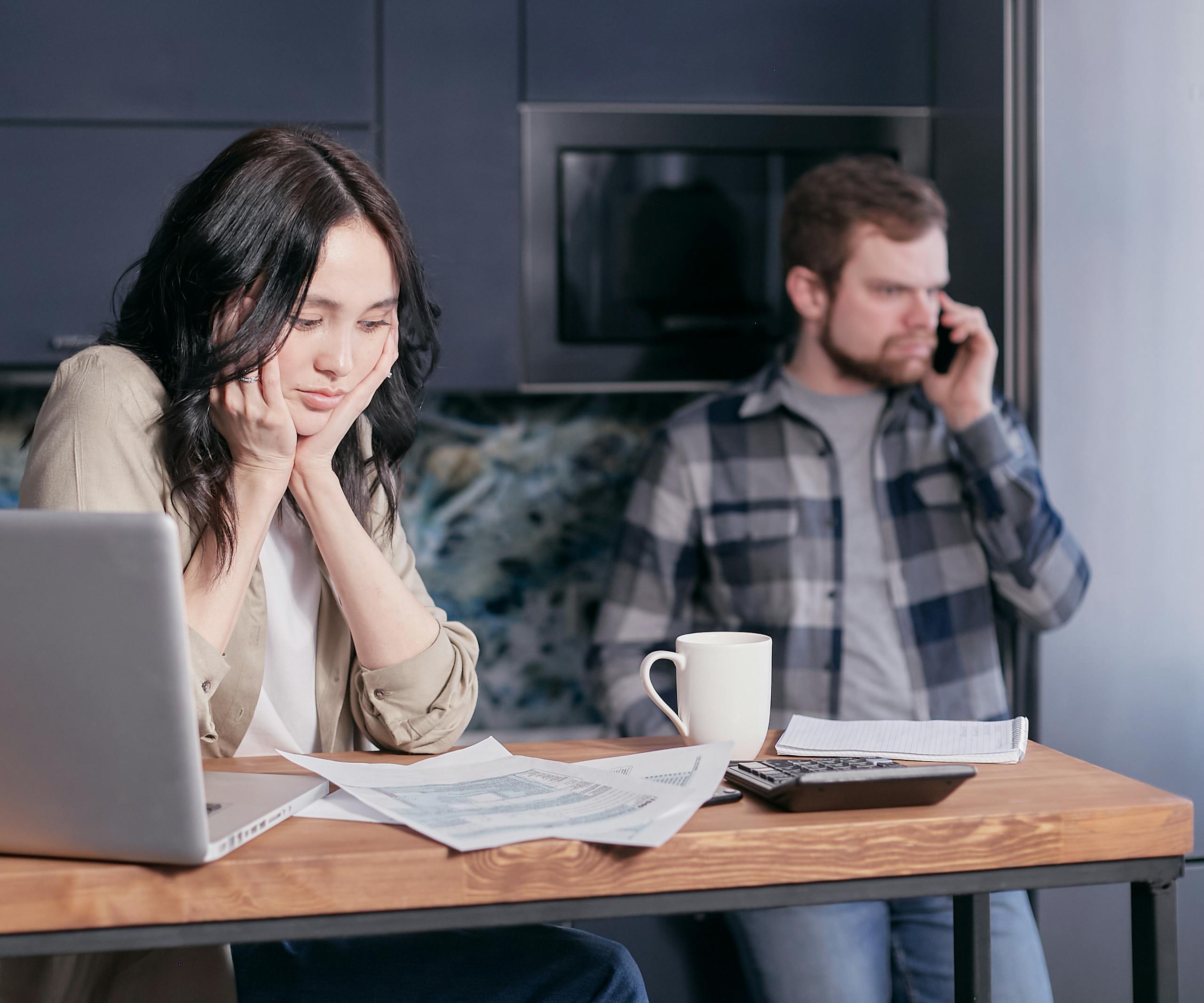 A couple working from home showing stress and communication issues over financial documents.