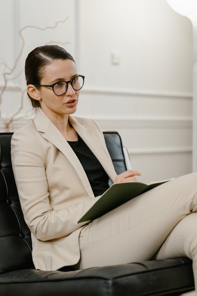 Confident woman in a blazer sitting and taking notes during a meeting in an office setting.
